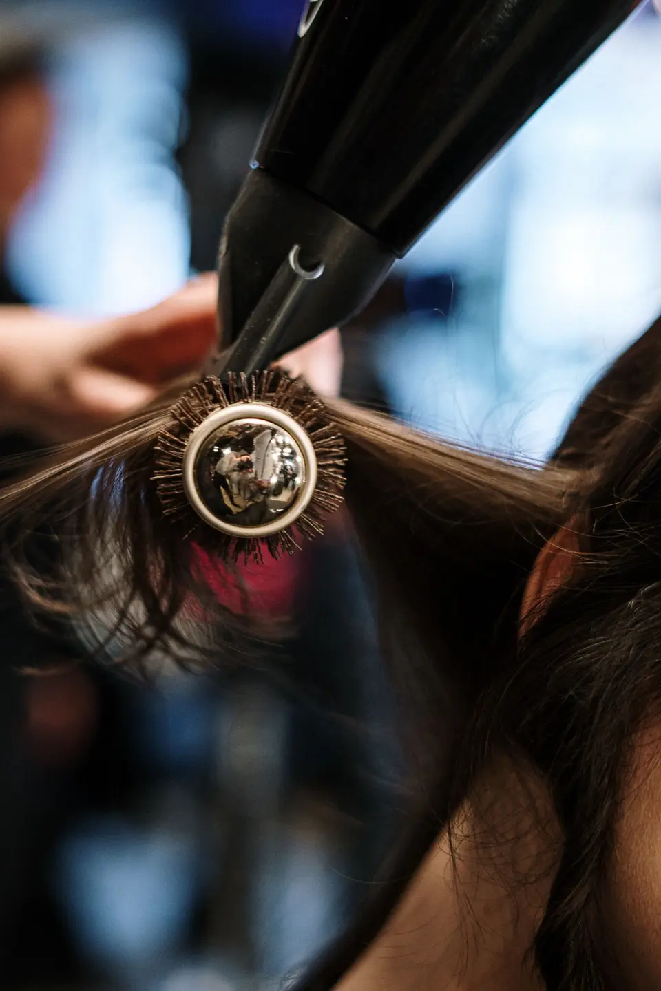 A stylist blow-drying a customer’s hair in a salon